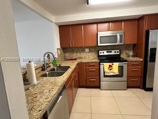 A kitchen features wood cabinets, granite countertops, and stainless steel appliances — 1100 NE 191st St # 24E, Miami FL 33179, MIAMI, FL