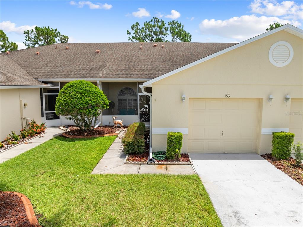 A single-story house with a beige stucco exterior, a one-car garage, and a screened entryway — 153 CLUB VILLAS LANE, KISSIMMEE, FL