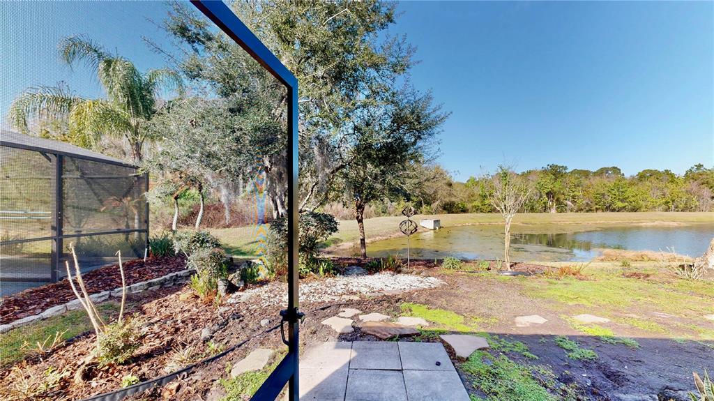 A view from a screened-in patio looking out toward a pond and wooded landscape — 3016 CRYSTAL CREEK BOULEVARD, ORLANDO, FL