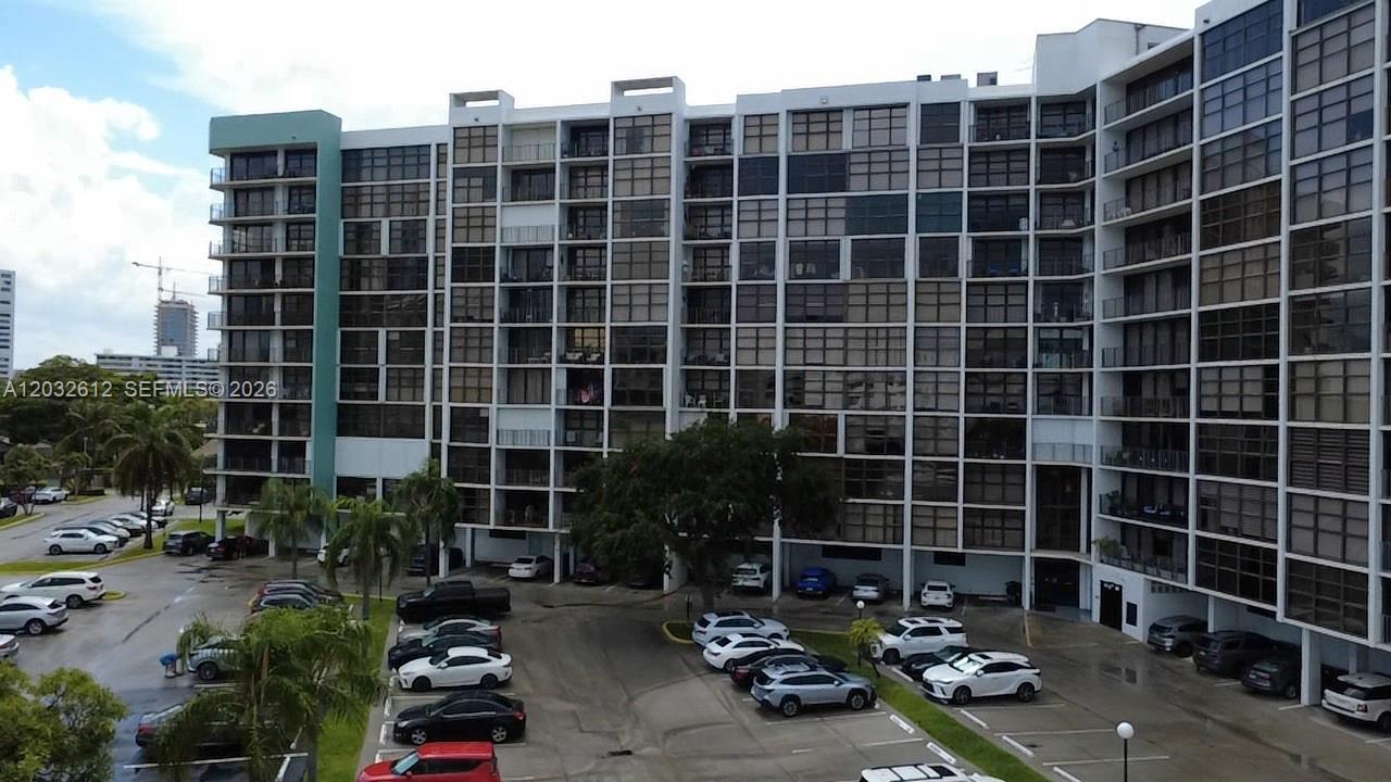 An exterior view of a multi-story apartment building with a parking lot in front — 400 Leslie Dr # 1124, Hallandale Beach FL 33009, HALLANDALE BEACH, FL