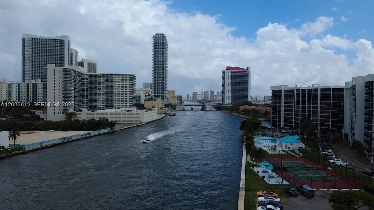 An aerial view shows a waterway flanked by high-rise apartment buildings and a tennis court — 400 Leslie Dr # 1124, Hallandale Beach FL 33009, HALLANDALE BEACH, FL
