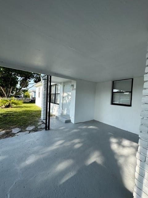 A covered concrete patio leads to the front entrance of a white house — 3904 SW 58th Ave, West Park FL 33023, WEST PARK, FL