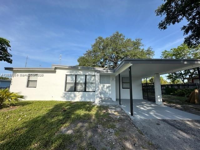 A white single-story house features a front carport and a grassy yard under a blue sky — 3904 SW 58th Ave, West Park FL 33023, WEST PARK, FL