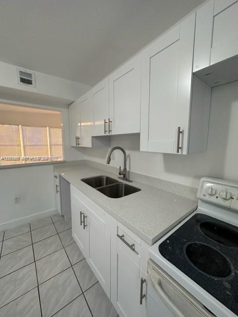 A kitchen features white cabinets, a double-basin sink, and a white electric stove — 3904 SW 58th Ave, West Park FL 33023, WEST PARK, FL