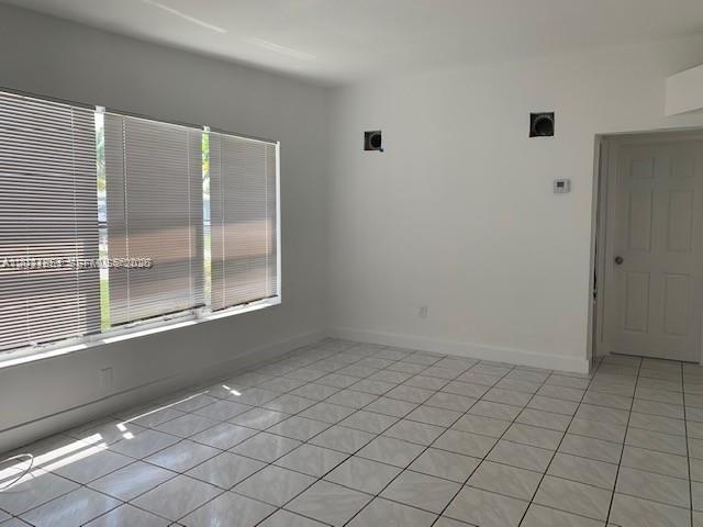 A room with white walls, tiled floors, large windows with blinds, and a closed door — 3904 SW 58th Ave, West Park FL 33023, WEST PARK, FL