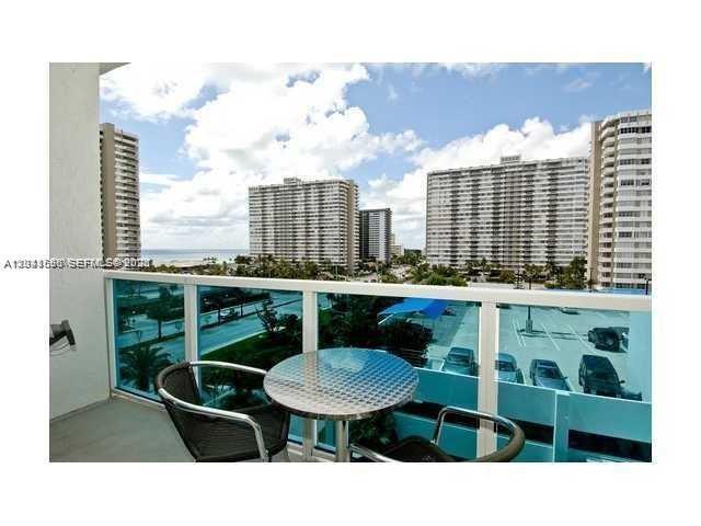 A balcony with a small metal table and two chairs overlooks a parking lot — 1945 S Ocean Dr # 602, Hallandale Beach FL 33009, HALLANDALE BEACH, FL
