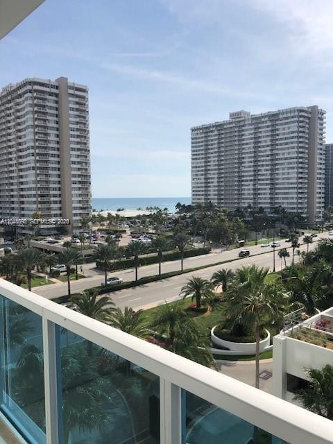 A high-angle view from a balcony overlooking a road, palm trees, and two tall buildings — 1945 S Ocean Dr # 602, Hallandale Beach FL 33009, HALLANDALE BEACH, FL