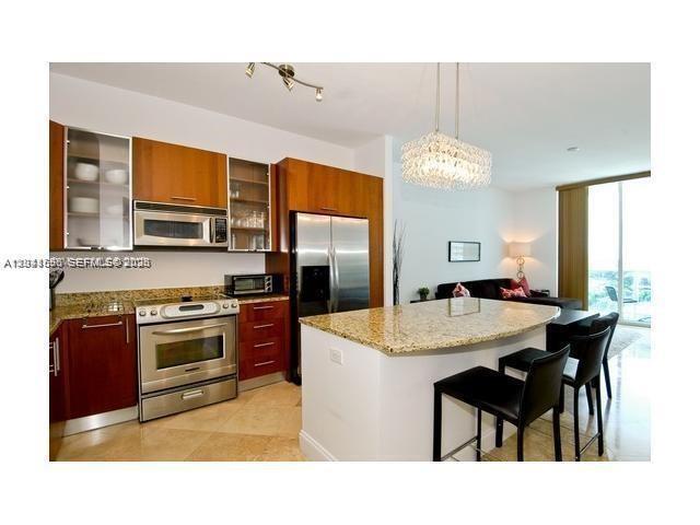 A kitchen with wood cabinets, stainless steel appliances, and a granite-topped island with bar stools — 1945 S Ocean Dr # 602, Hallandale Beach FL 33009, HALLANDALE BEACH, FL