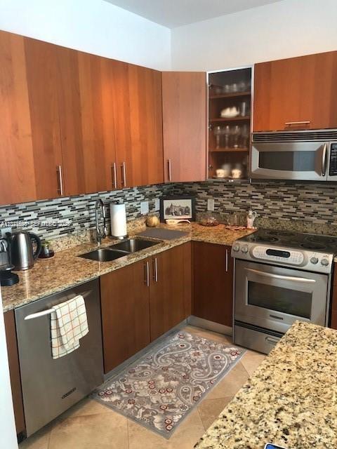 A kitchen features wood cabinets, stainless steel appliances, and a granite countertop — 1945 S Ocean Dr # 602, Hallandale Beach FL 33009, HALLANDALE BEACH, FL