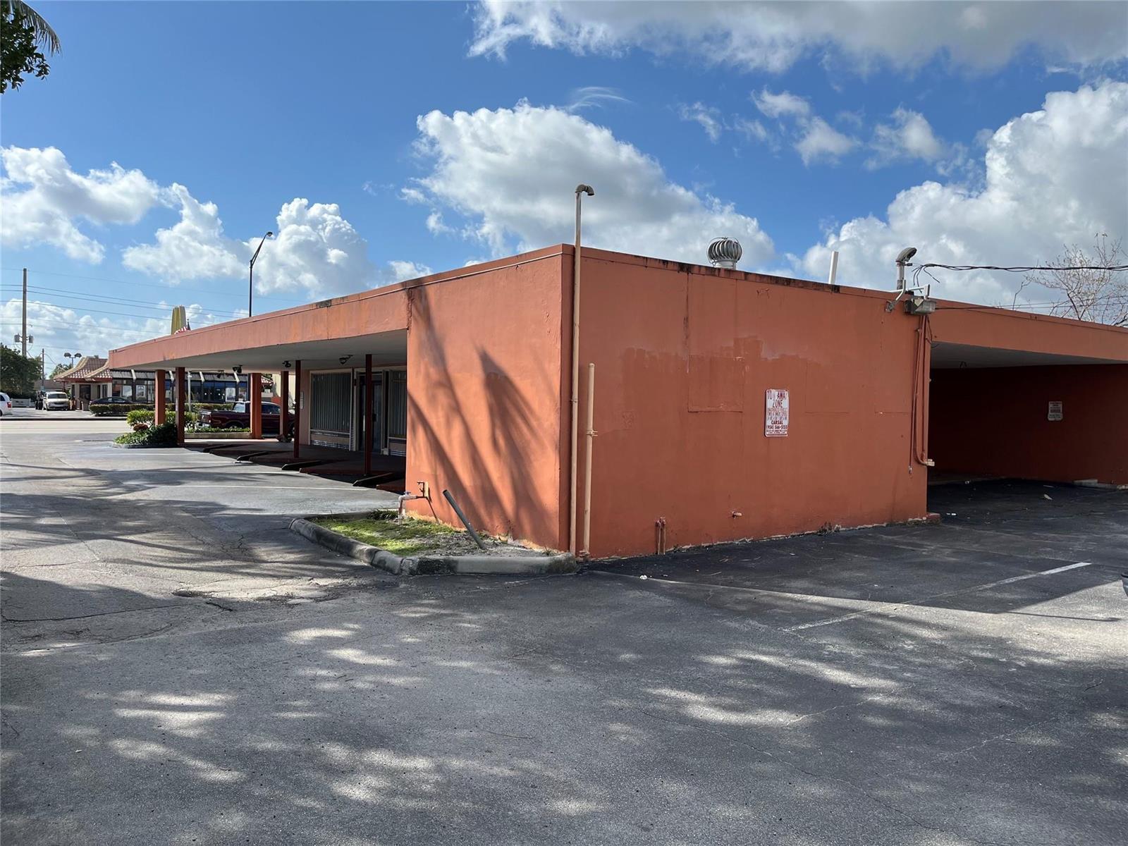 A low-slung, orange commercial building with a covered parking area under a blue sky — 1361 E Commercial Boulevard, Oakland Park FL 33334, OAKLAND PARK, FL