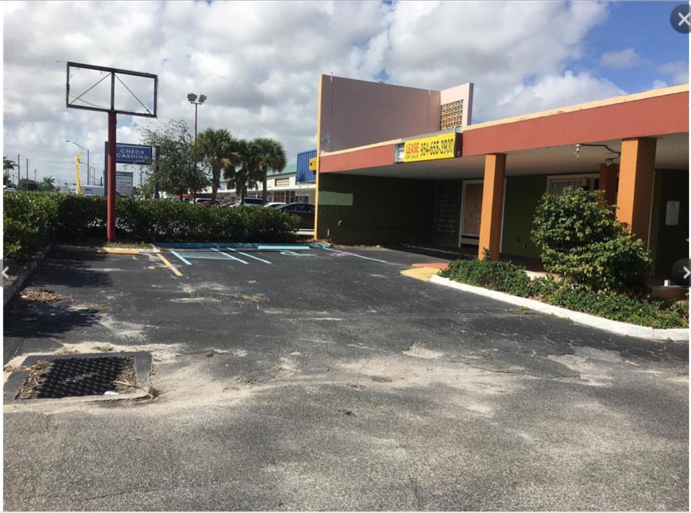 An exterior view of a vacant commercial building with a parking lot and handicap space — 1361 E Commercial Boulevard, Oakland Park FL 33334, OAKLAND PARK, FL