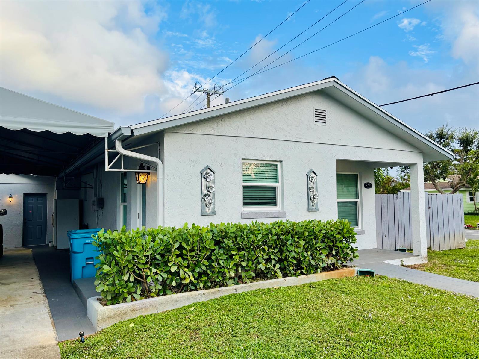 A single-story house with a white stucco exterior, a covered carport, and a front hedge — 222 SE 3rd Street, Boynton Beach FL 33435, BOYNTON BEACH, FL