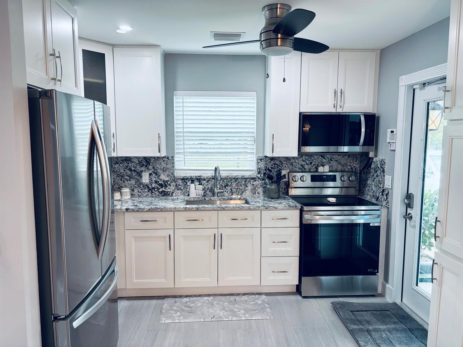 A kitchen featuring white cabinets, stainless steel appliances, and a dark granite countertop — 222 SE 3rd Street, Boynton Beach FL 33435, BOYNTON BEACH, FL