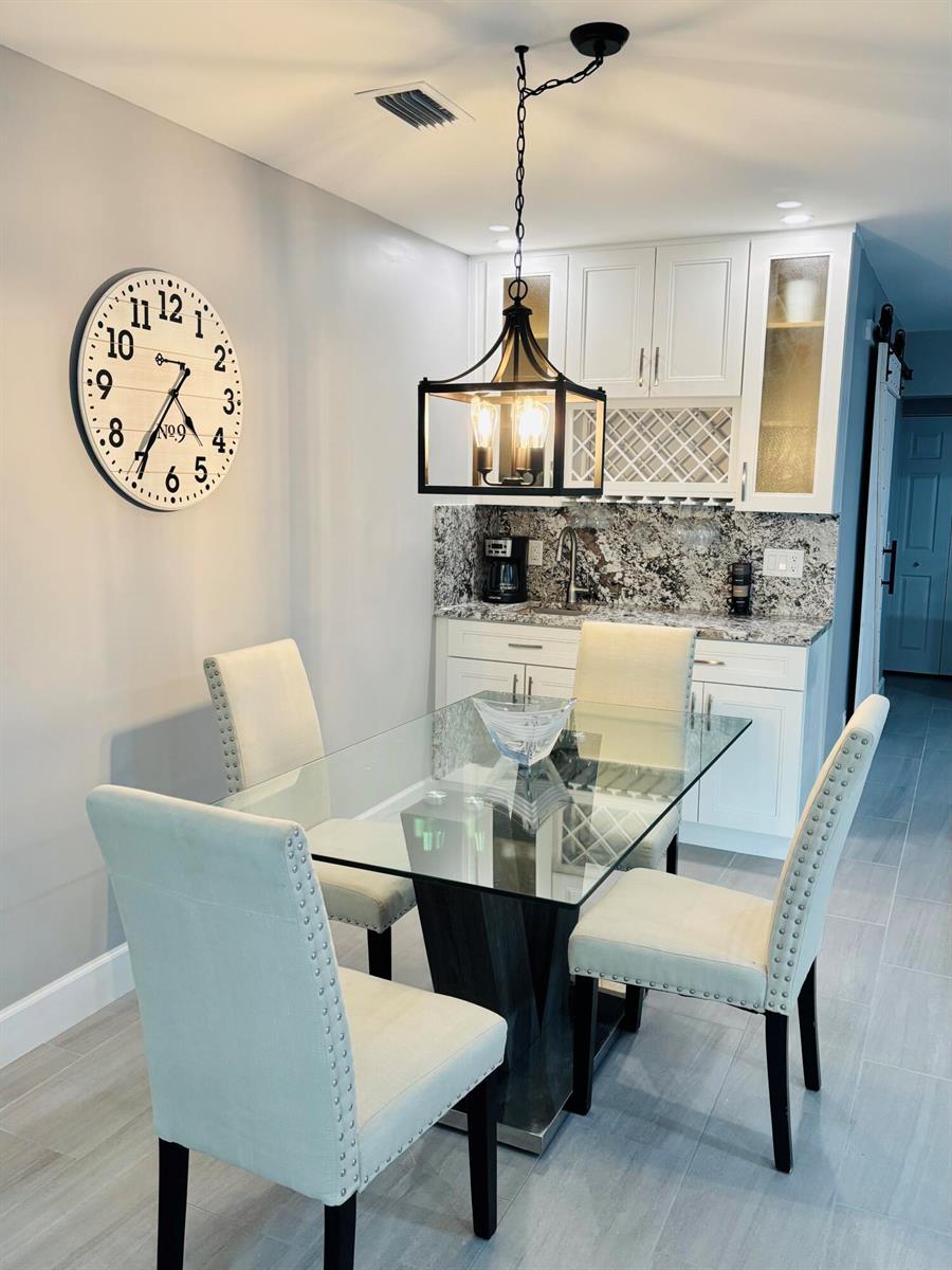 A dining area features a glass-topped table, four upholstered chairs, a wall clock, and cabinetry — 222 SE 3rd Street, Boynton Beach FL 33435, BOYNTON BEACH, FL