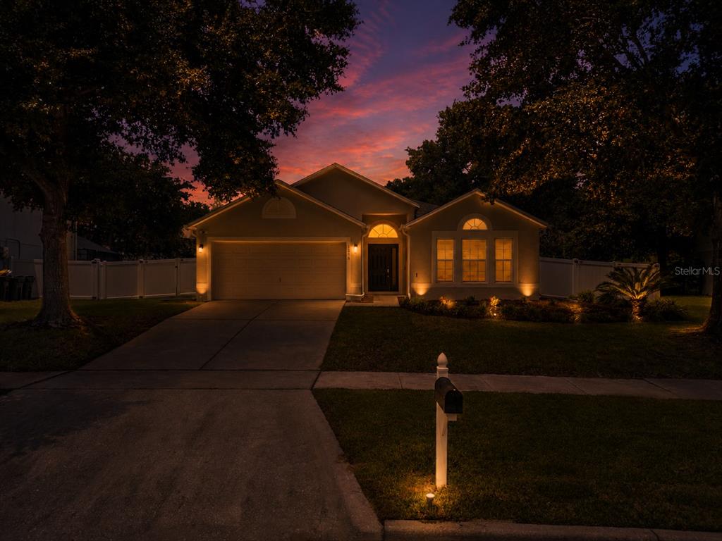 A single-story house with a garage and illuminated windows at sunset — 3216 PARK BRANCH AVENUE, CLERMONT, FL