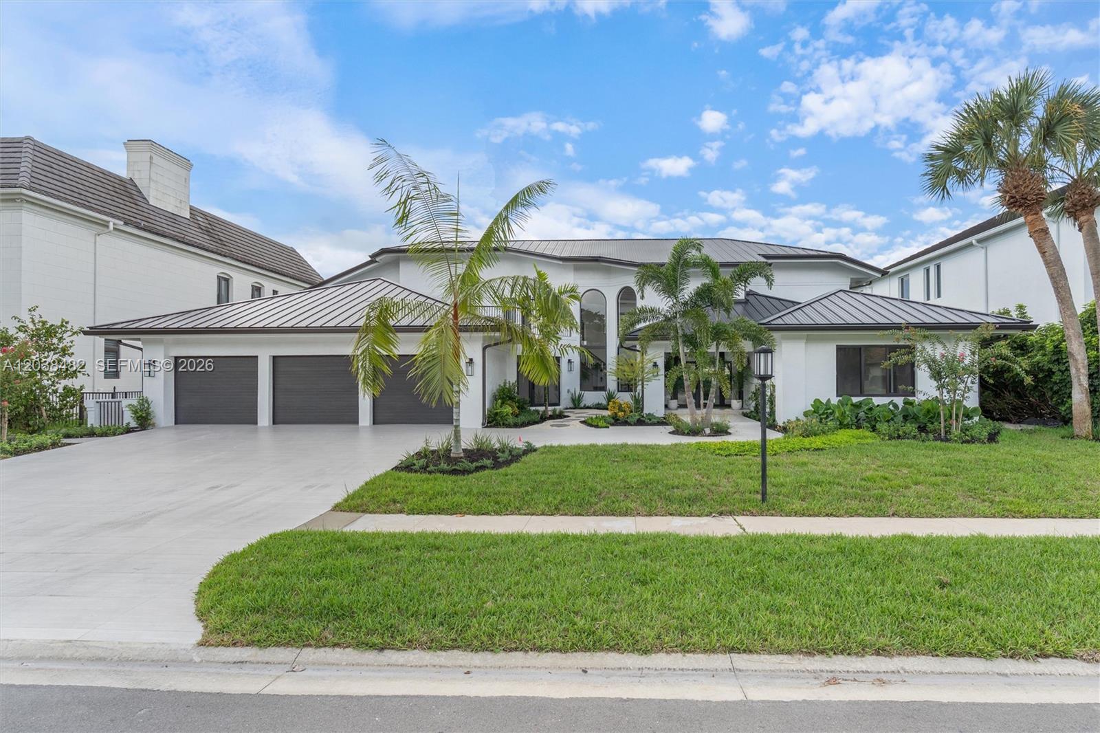 A modern white house with a metal roof, three-car garage, and palm trees in front — 7190 Valencia Dr, Boca Raton FL 33433, BOCA RATON, FL