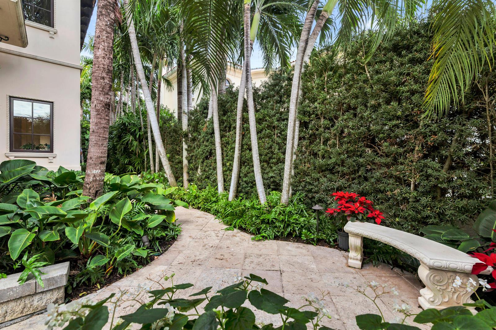A stone path winds through a lush garden with palm trees and a stone bench — 261 Seminole Avenue, Palm Beach FL 33480, PALM BEACH, FL