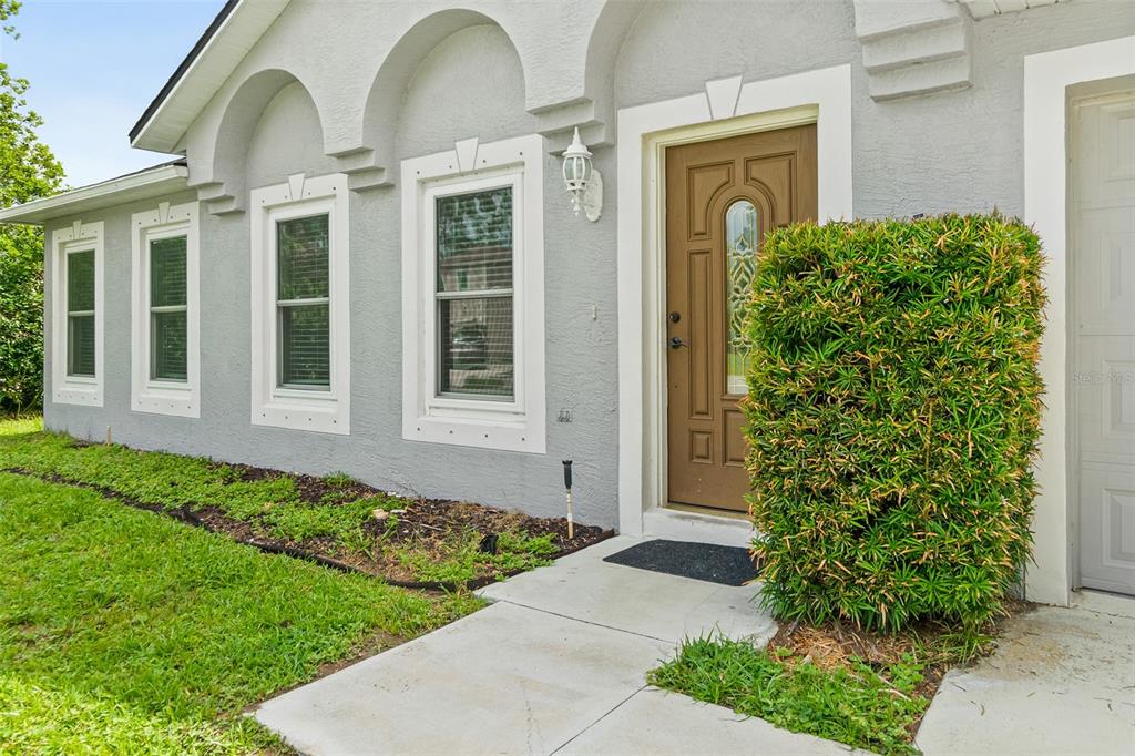 A gray house exterior features a brown front door, white trim, and a manicured hedge — 51 BEAVERDAM LANE, PALM COAST, FL
