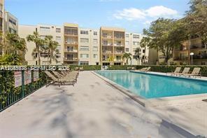 A swimming pool sits on a patio in front of a multi-story apartment building — 14250 SW 62nd St # 312, Miami FL 33183, MIAMI, FL