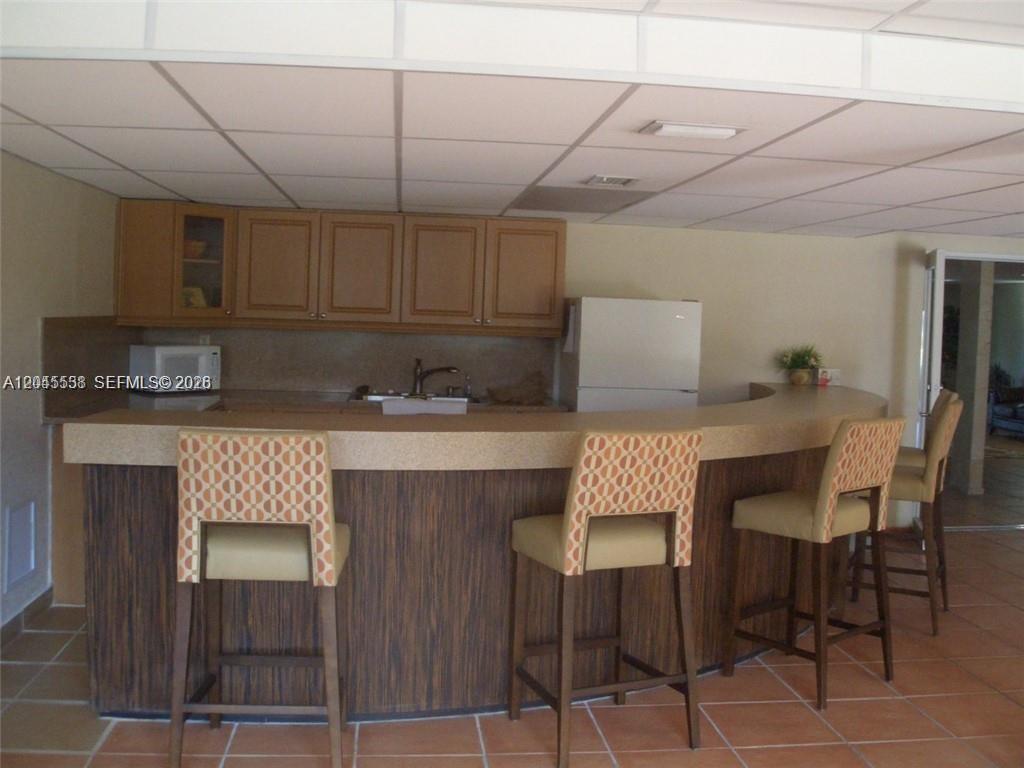 A kitchen features a curved bar, wooden cabinets, and a drop ceiling with recessed lighting — 14250 SW 62nd St # 312, Miami FL 33183, MIAMI, FL