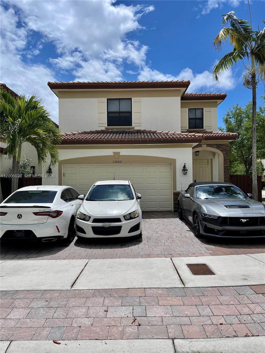 A two-story house exterior features a beige stucco facade, a tiled roof, and a garage — 10086 NW 89th Ter, Doral FL 33178, DORAL, FL