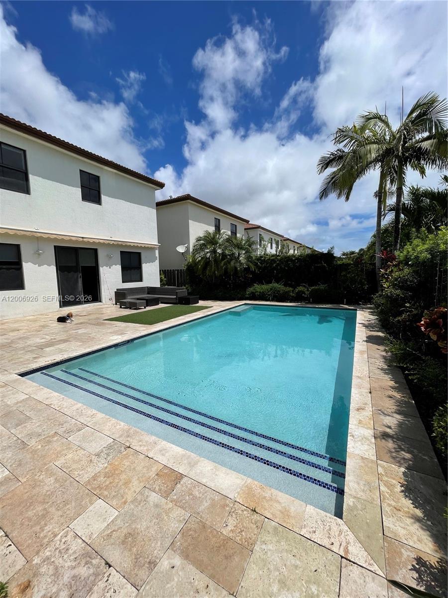 A backyard features a rectangular swimming pool with steps, a patio, and a small lawn — 10086 NW 89th Ter, Doral FL 33178, DORAL, FL