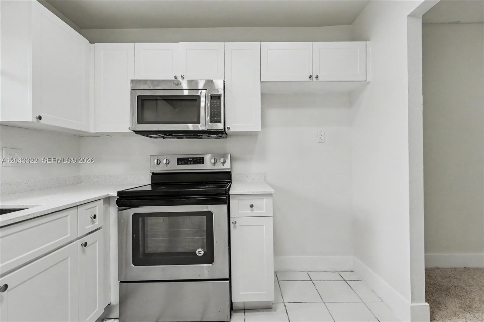 A kitchen features white cabinets, stainless steel appliances, and white tiled flooring — 5300 Washington St # K229, Hollywood FL 33021, HOLLYWOOD, FL