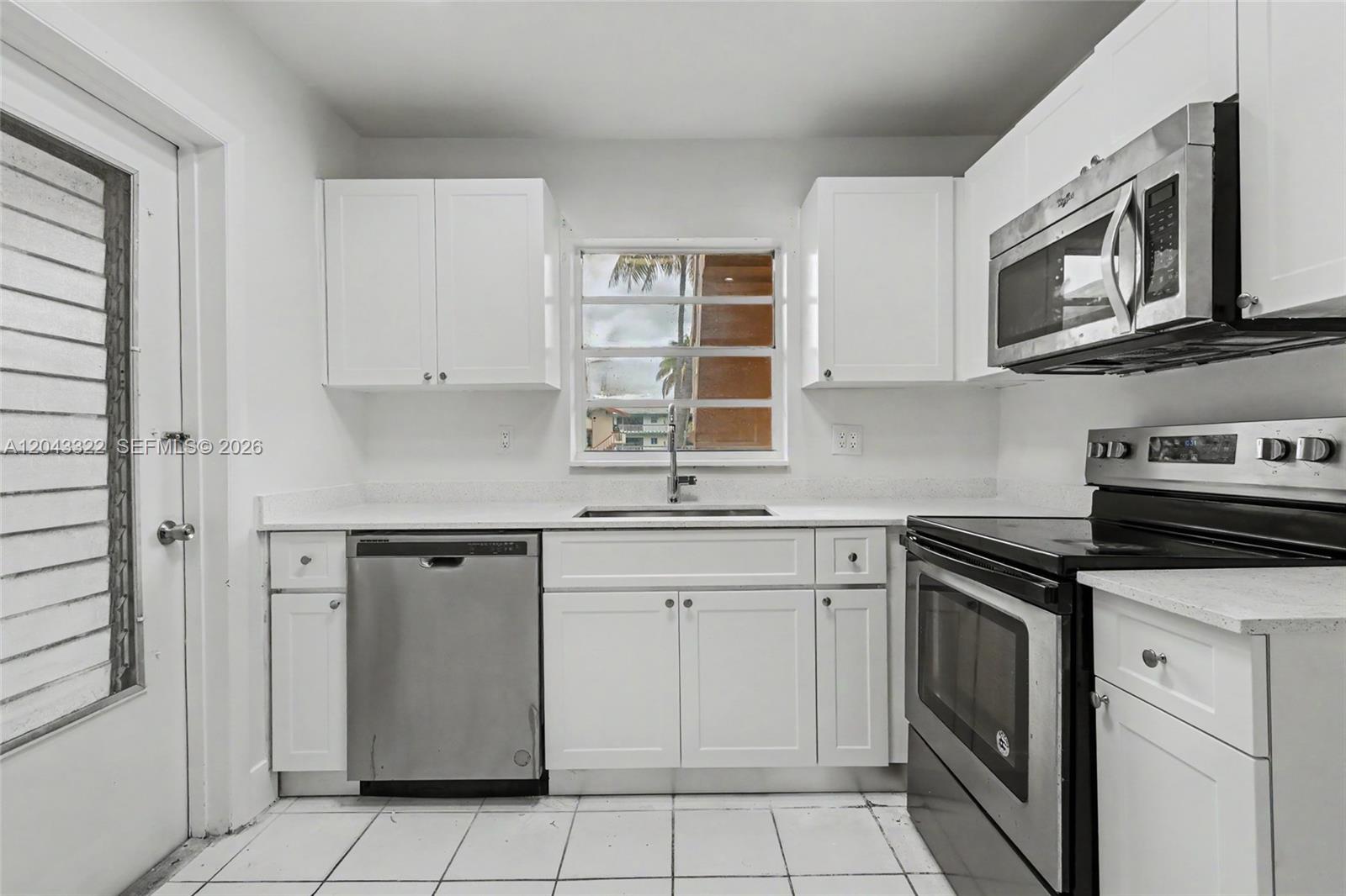 A kitchen features white cabinets, stainless steel appliances, white countertops, and white tile flooring — 5300 Washington St # K229, Hollywood FL 33021, HOLLYWOOD, FL