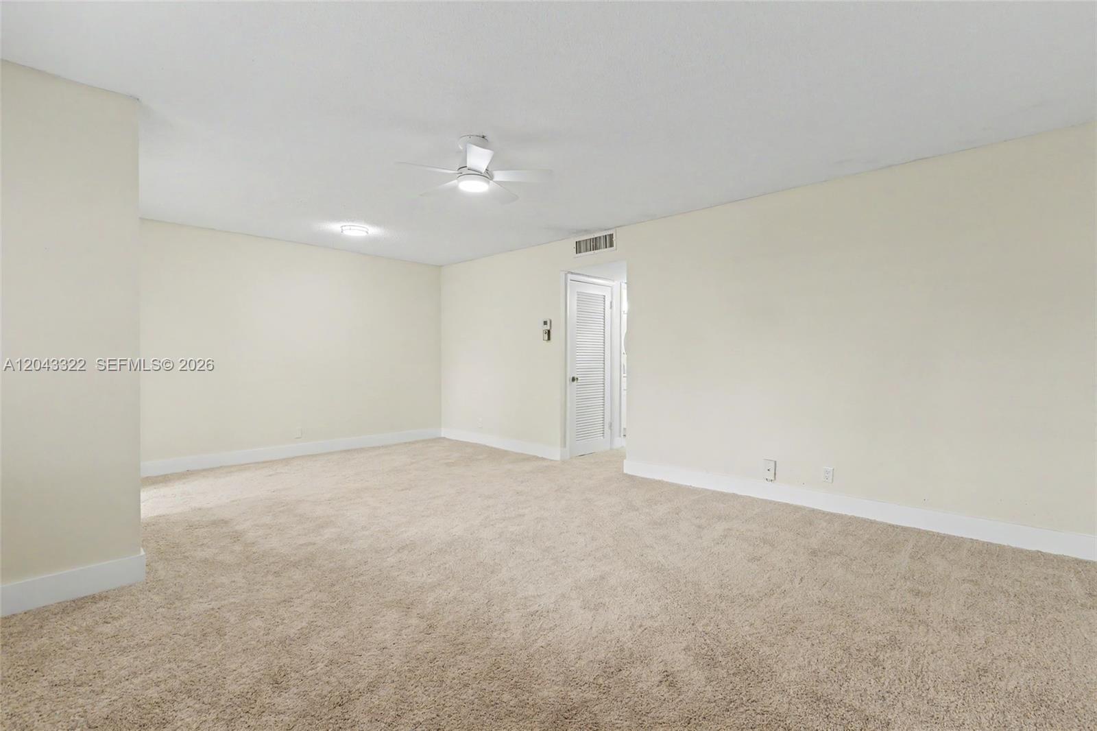 An empty room features beige carpeting, cream-colored walls, a ceiling fan, and a louvered door — 5300 Washington St # K229, Hollywood FL 33021, HOLLYWOOD, FL