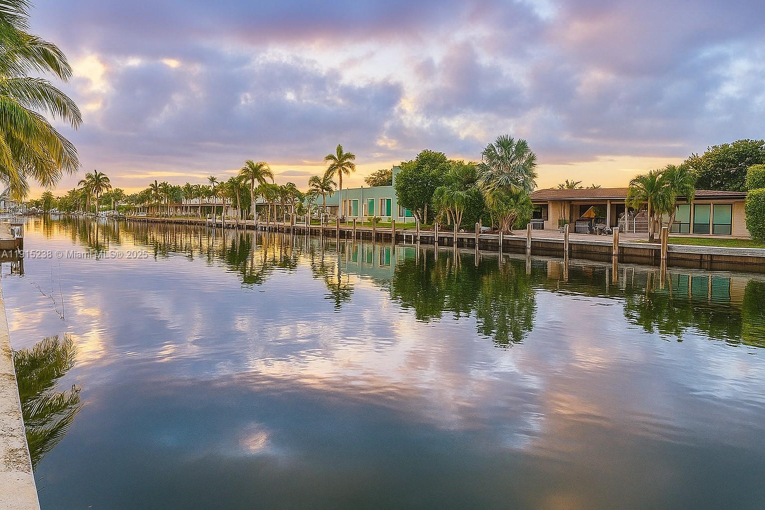 A canal reflects the sunset, palm trees, and waterfront houses with wooden docks — 1100 Pine Dr # 106, Pompano Beach FL 33060, POMPANO BEACH, FL