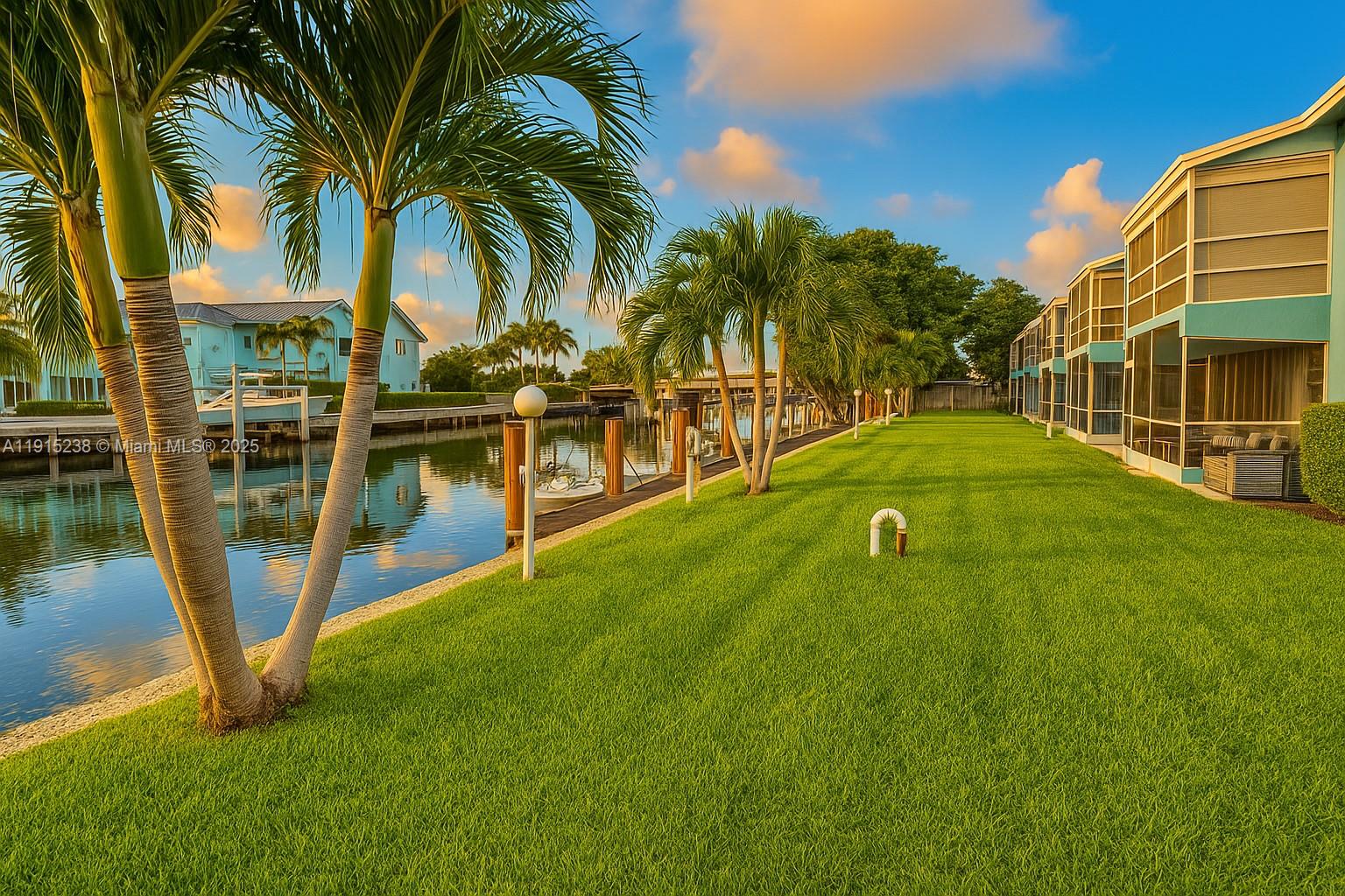 A grassy lawn borders a canal with palm trees and multi-story residential buildings — 1100 Pine Dr # 106, Pompano Beach FL 33060, POMPANO BEACH, FL