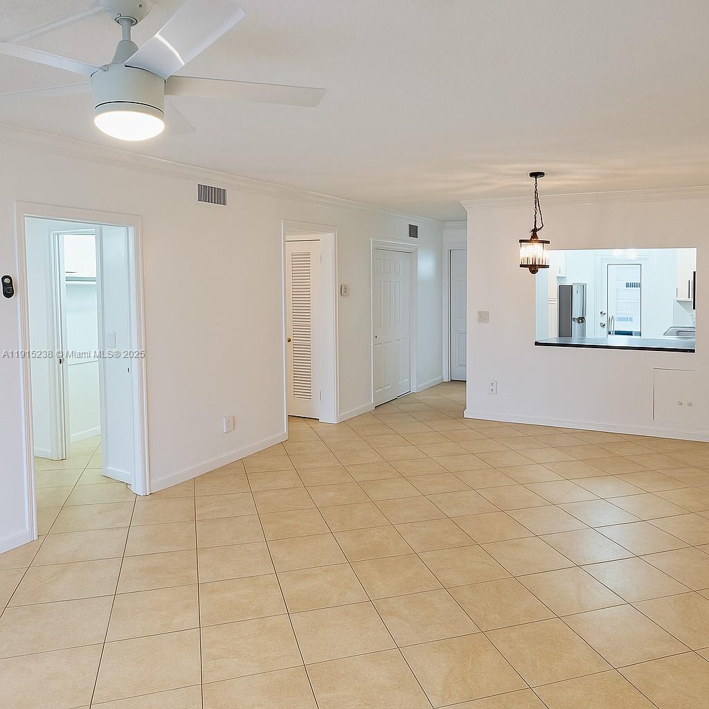 An interior view shows a living area with tile floors, a ceiling fan, and a kitchen pass-through — 1100 Pine Dr # 106, Pompano Beach FL 33060, POMPANO BEACH, FL