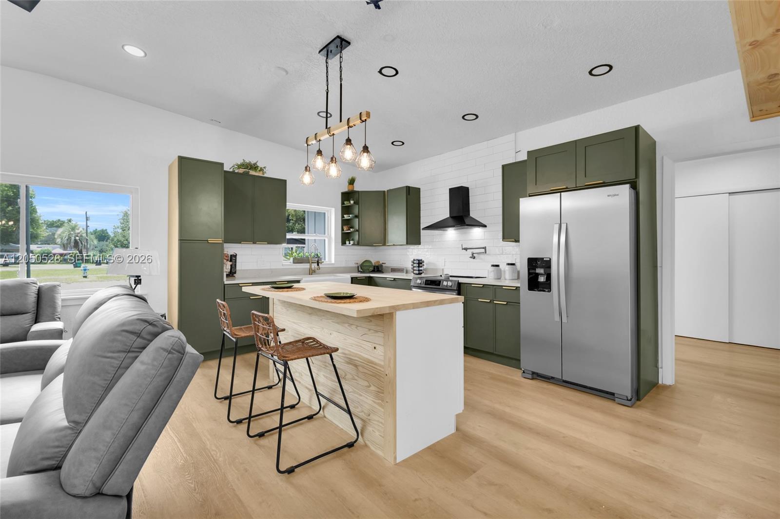 A kitchen features olive green cabinets, a light wood island, and stainless steel appliances — ORLANDO, FL
