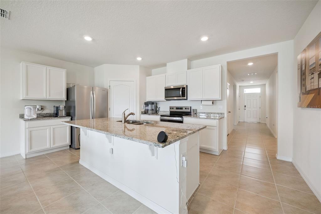 A kitchen featuring white cabinets, granite countertops, a center island, and stainless steel appliances — 5087 TANA TERRACE, ST CLOUD, FL