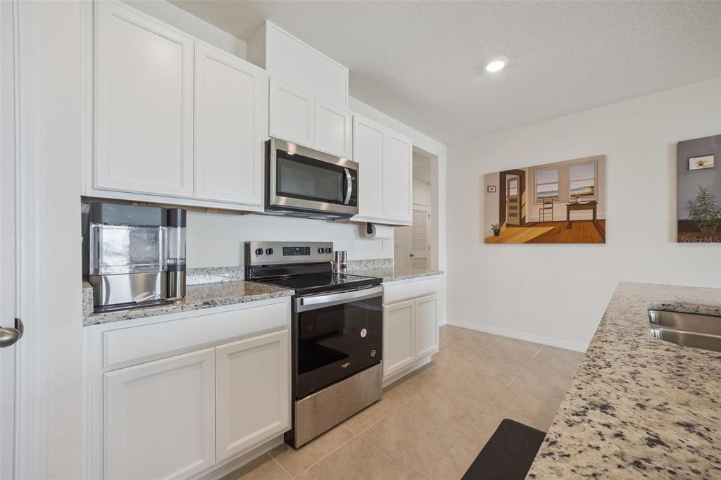 A kitchen features white cabinets, granite countertops, and stainless steel appliances — 5087 TANA TERRACE, ST CLOUD, FL