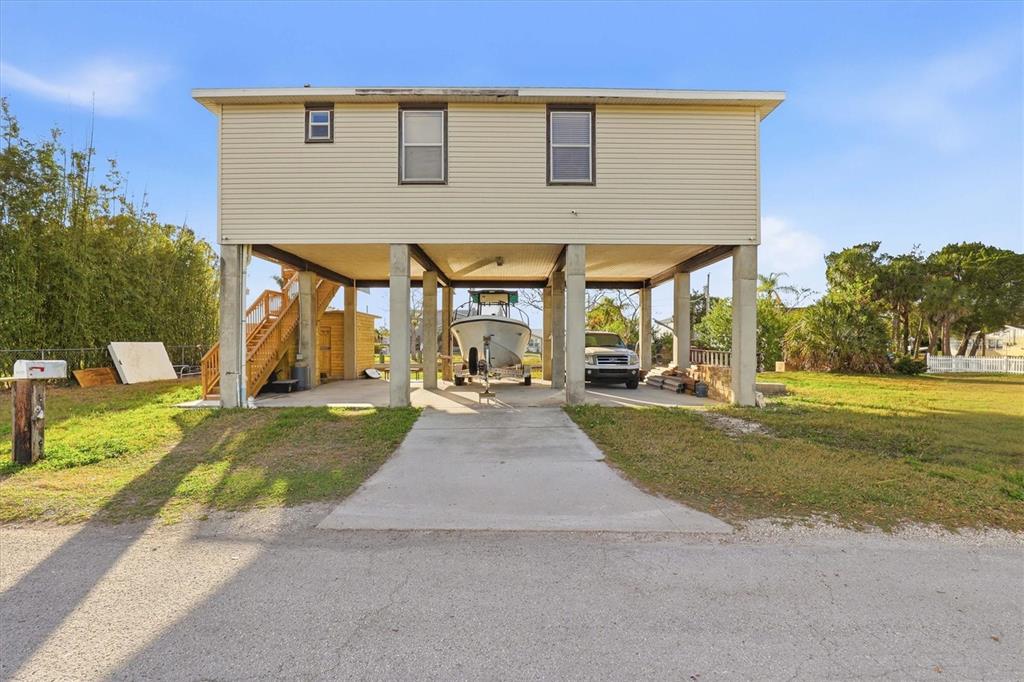 A stilt house with a boat and truck parked underneath on a concrete driveway — 14203 SHILOH COURT, HUDSON, FL