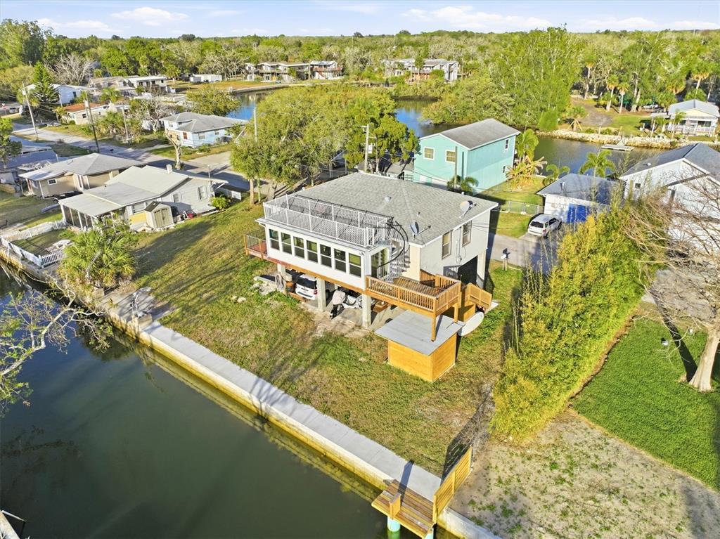 An elevated house with a rooftop deck and spiral staircase sits along a canal — 14203 SHILOH COURT, HUDSON, FL