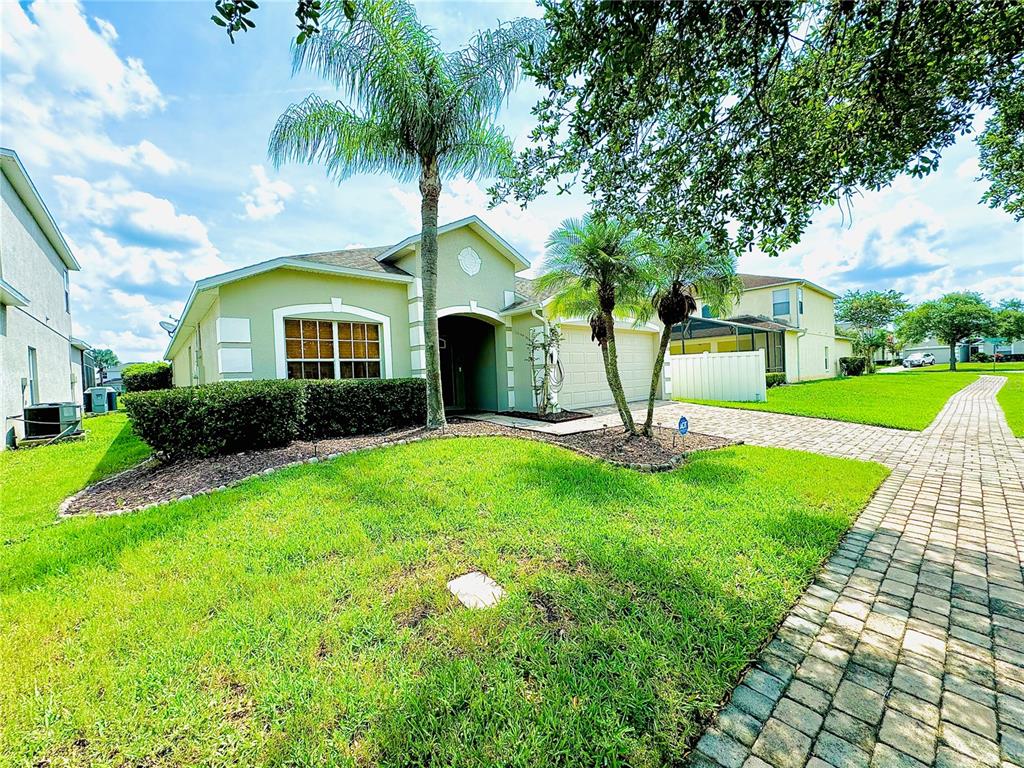 A light green single-story house with a palm tree, paved driveway, and manicured lawn — 4647 CUMBRIAN LAKES DRIVE, KISSIMMEE, FL