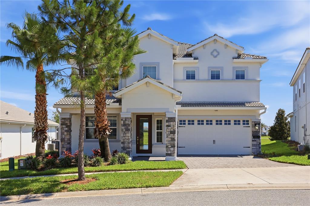 A two-story suburban house with a stone-accented entryway, a two-car garage, and palm trees — 1463 BUNKER DRIVE, DAVENPORT, FL