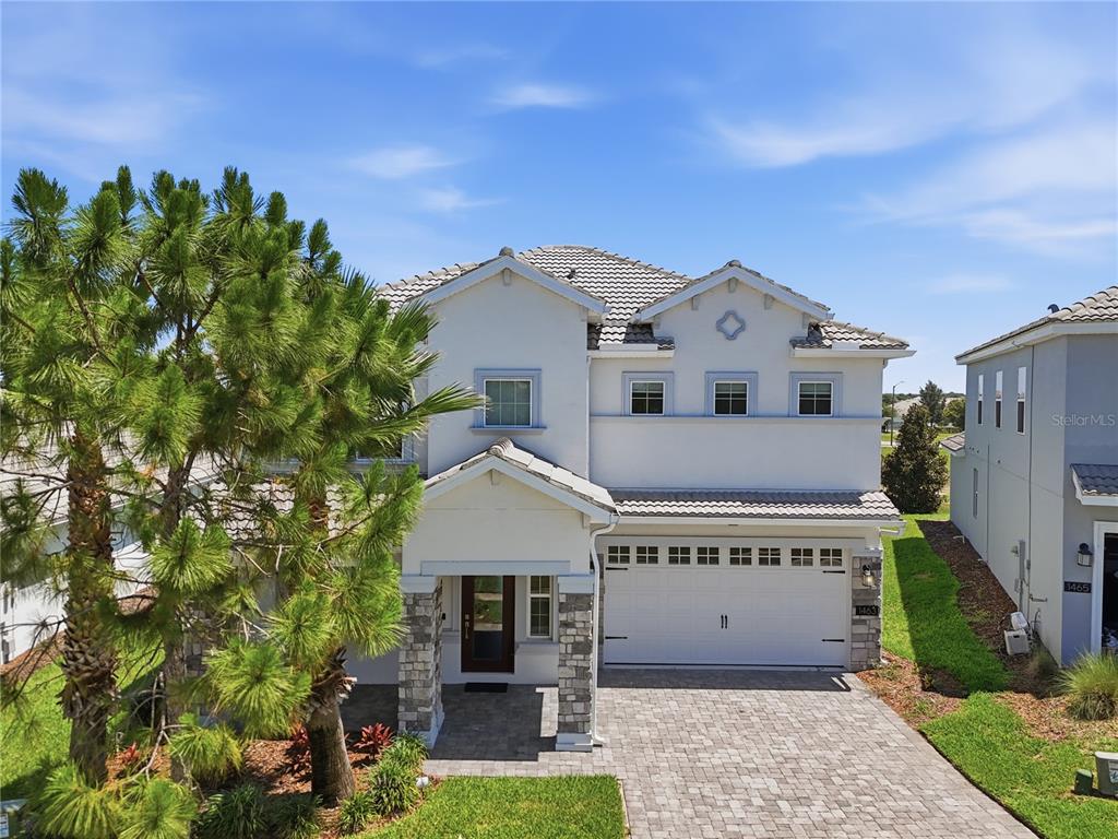 A two-story house with a stone-accented entryway, white stucco exterior, and a paved driveway — 1463 BUNKER DRIVE, DAVENPORT, FL
