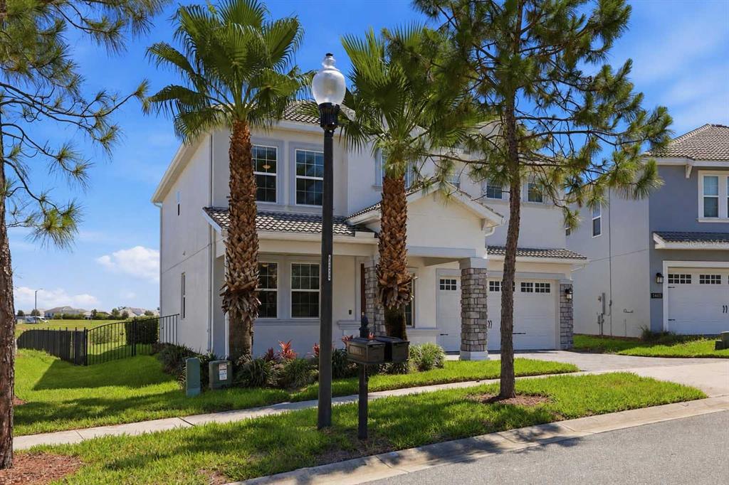 A two-story house with a light-colored stucco exterior, stone accents, and two palm trees — 1463 BUNKER DRIVE, DAVENPORT, FL