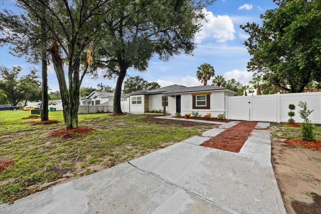 A white single-story house with a concrete driveway and a white vinyl privacy fence — 8730 N CALDER PLACE, TAMPA, FL