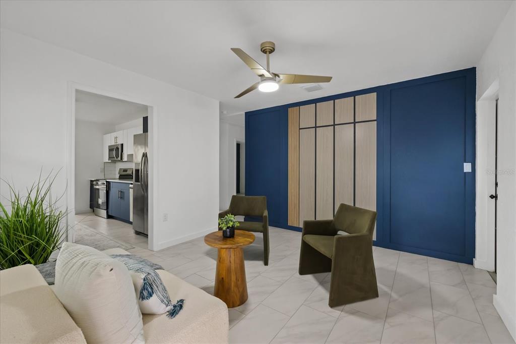 A living room features a blue accent wall with wood paneling, tile floors, and two chairs — 8730 N CALDER PLACE, TAMPA, FL