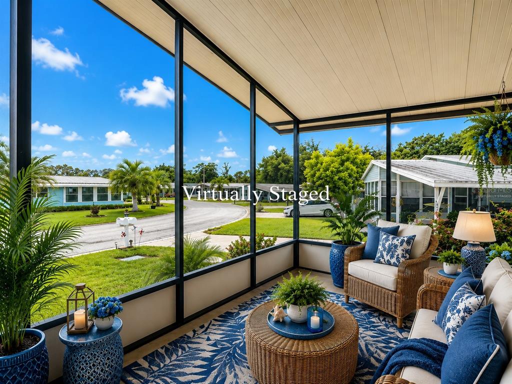 A screened-in porch features wicker furniture, a blue patterned rug, and views of a neighborhood — 4919 BLANCO DRIVE, ZEPHYRHILLS, FL