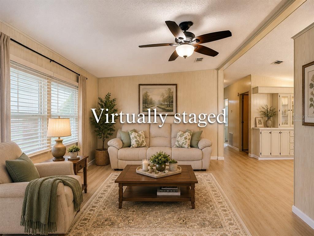 A living room with light wood-look flooring, a ceiling fan, and virtual furniture staging — 4919 BLANCO DRIVE, ZEPHYRHILLS, FL