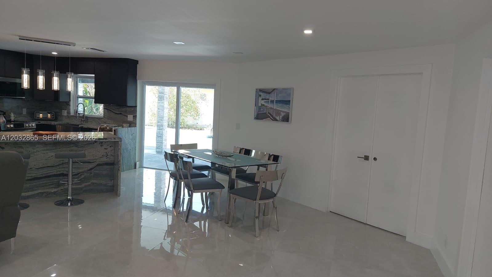 A modern dining area features a glass table, metal chairs, and a nearby kitchen island — 320 SE 15 PL, Cape Coral FL 33990, CAPE CORAL, FL
