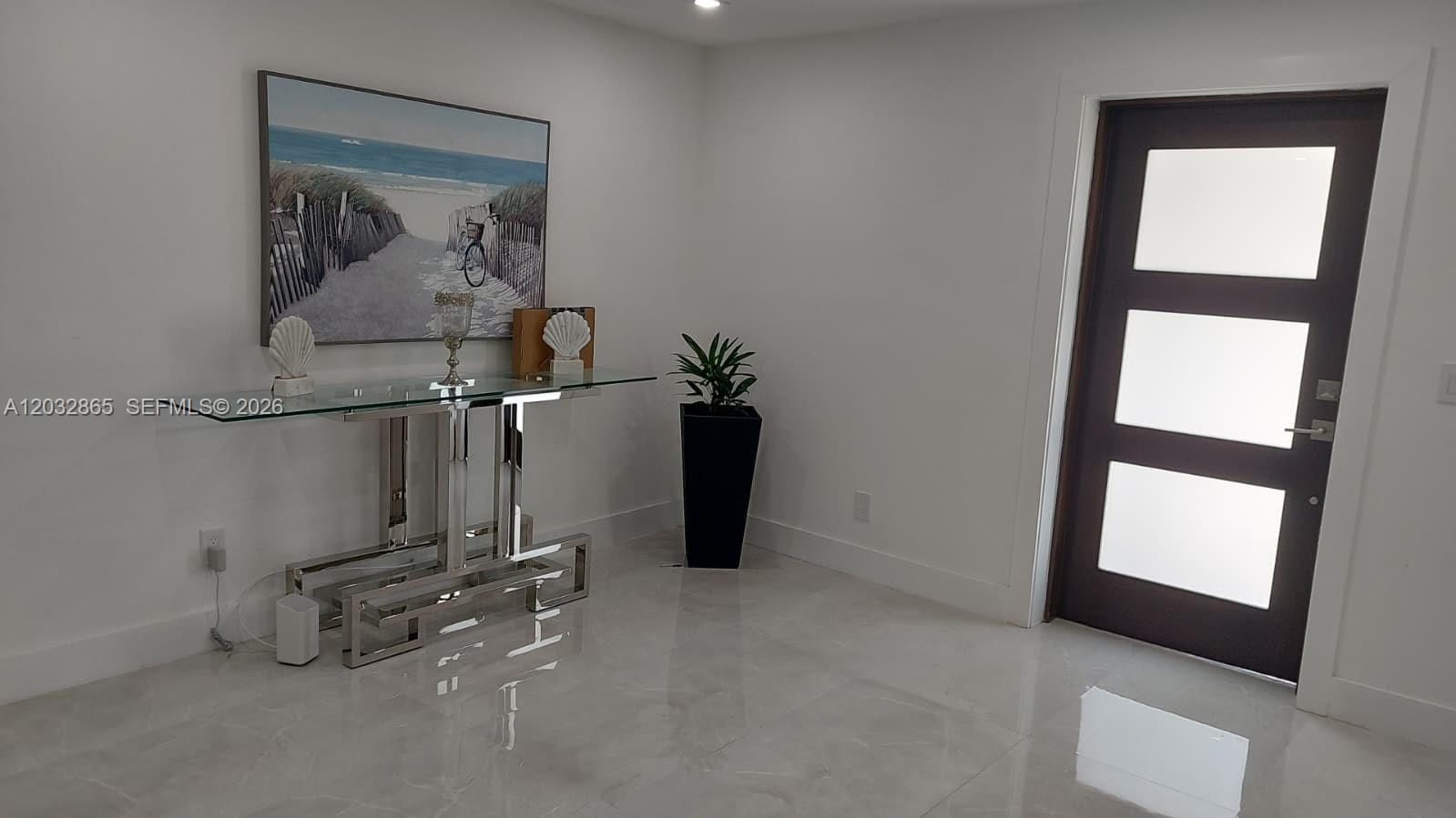 A modern entryway features a glass console table, coastal wall art, and a frosted-glass door — 320 SE 15 PL, Cape Coral FL 33990, CAPE CORAL, FL