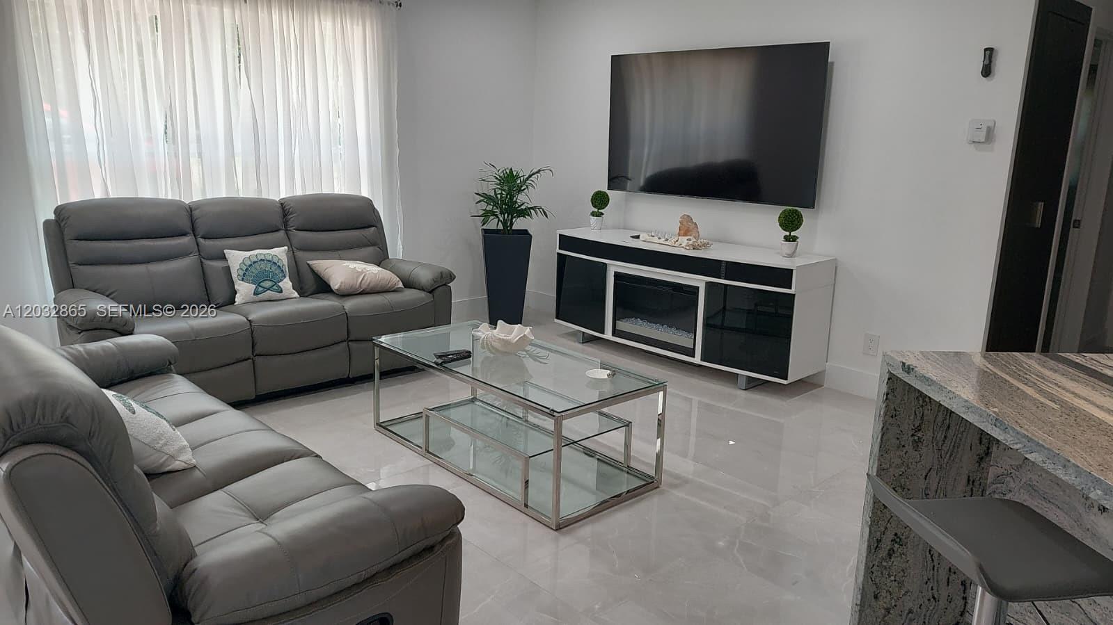 A living room features gray leather sofas, a glass coffee table, and a media console — 320 SE 15 PL, Cape Coral FL 33990, CAPE CORAL, FL