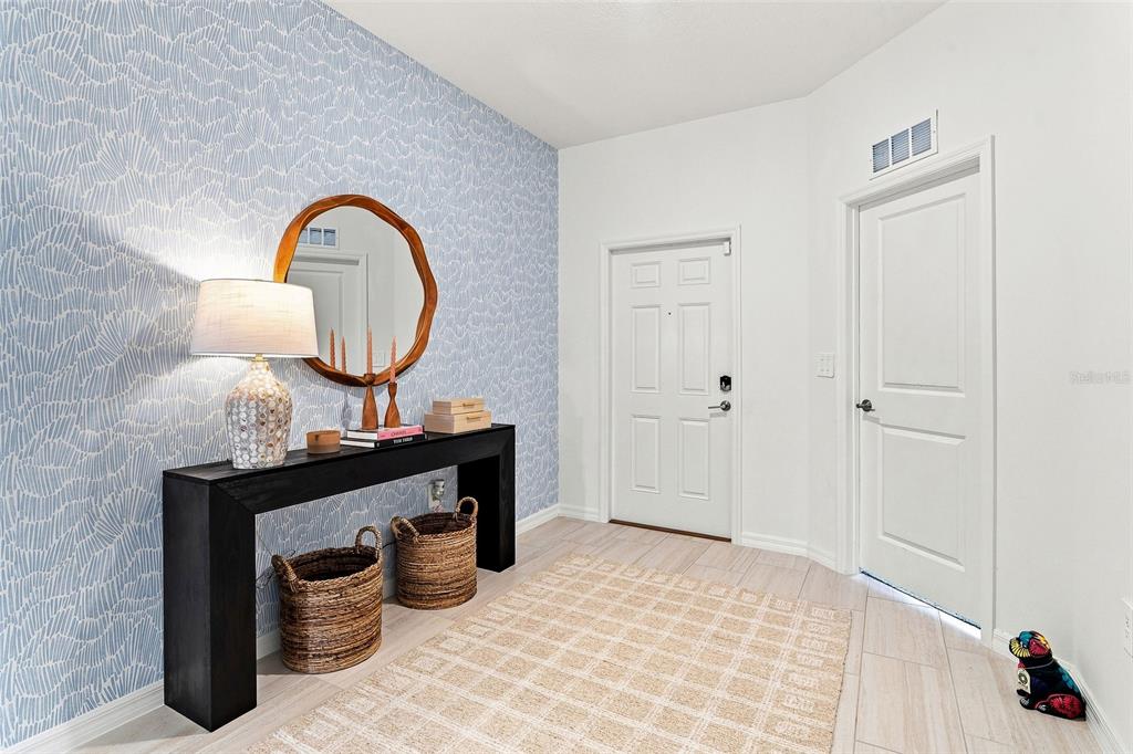 An entryway features a patterned blue accent wall, a black console table, and a rug — 15173 RAINBOW QUARTZ STREET, WIMAUMA, FL
