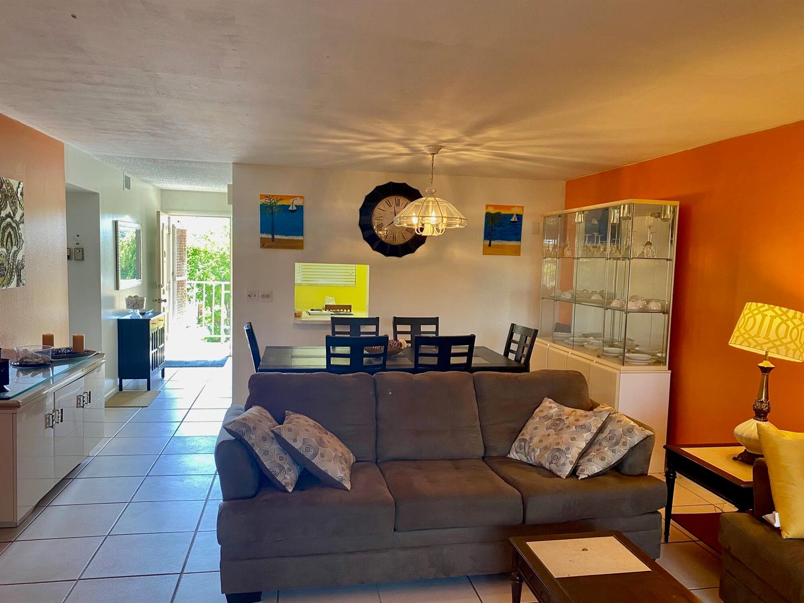 A living room and dining area with tile floors, a brown sofa, and orange walls — 2615 NE 3rd Court # 302, Boynton Beach FL 33435, BOYNTON BEACH, FL